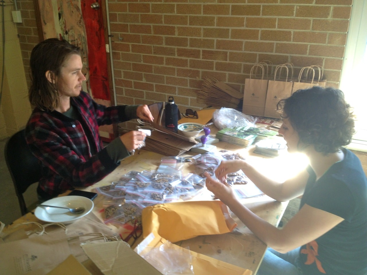 Michael and Gi preparing 200 thank you bags of seeds and such (thought this would be stacks but we ran out by Midday...)