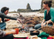 Kirsten Bradley & Fiona Weir sharing a joyful meal by a campfire at Kiama beach. Image from a post on sustainable holiday projects.