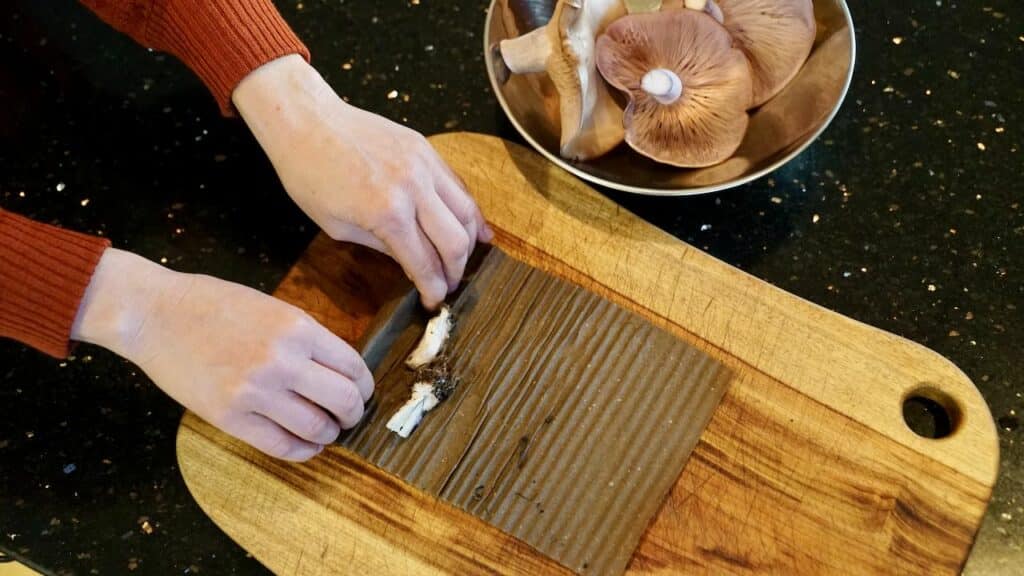 two hands rolling up the stem butts into the piece of corrugated cardboard