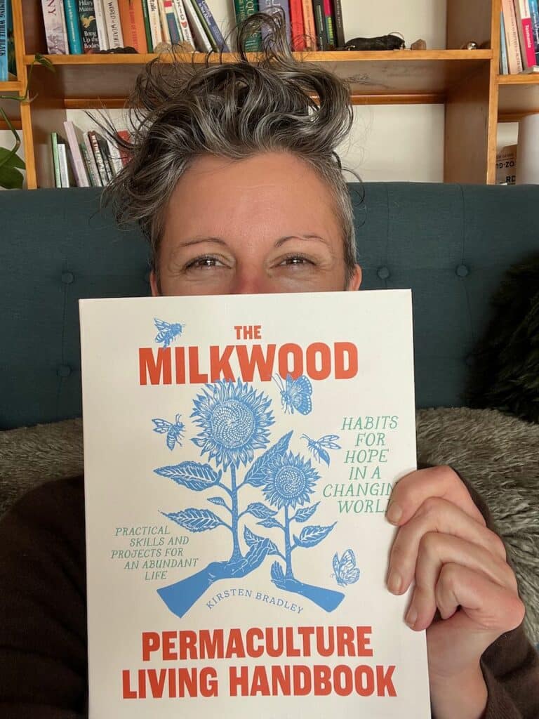 Kirsten Bradley, the author, hiding behind her new book. The Permaculture Living Handbook.