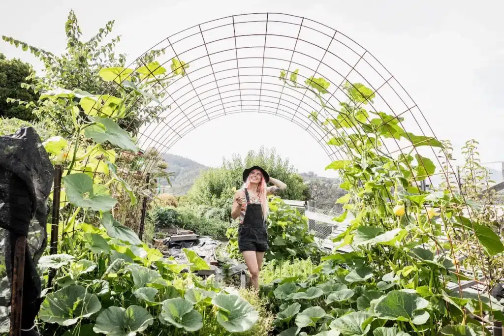 Hannah Moloney under a trellis arch in a thriving veggie garden