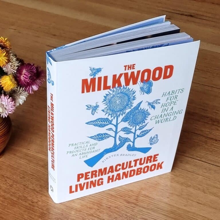 The Milkwood Permaculture Living Handbook standing on a wooden table