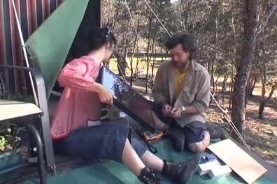 Solar Power! (albeit on a small scale) (video still) Two people sitting outside a tent unpacking a small solar panel