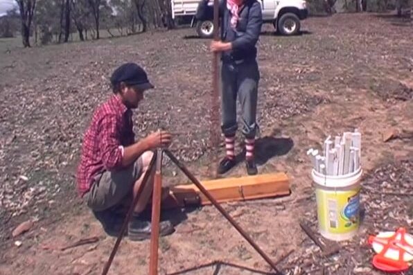 Surveying with a dumpy level and staff, a ute parked behind