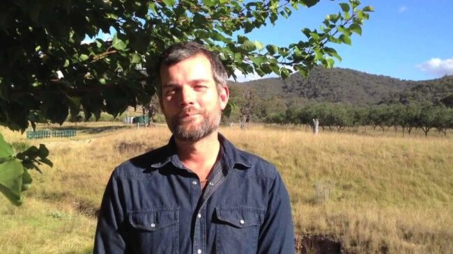 Nick Ritar standing in a sunny paddock under a tree