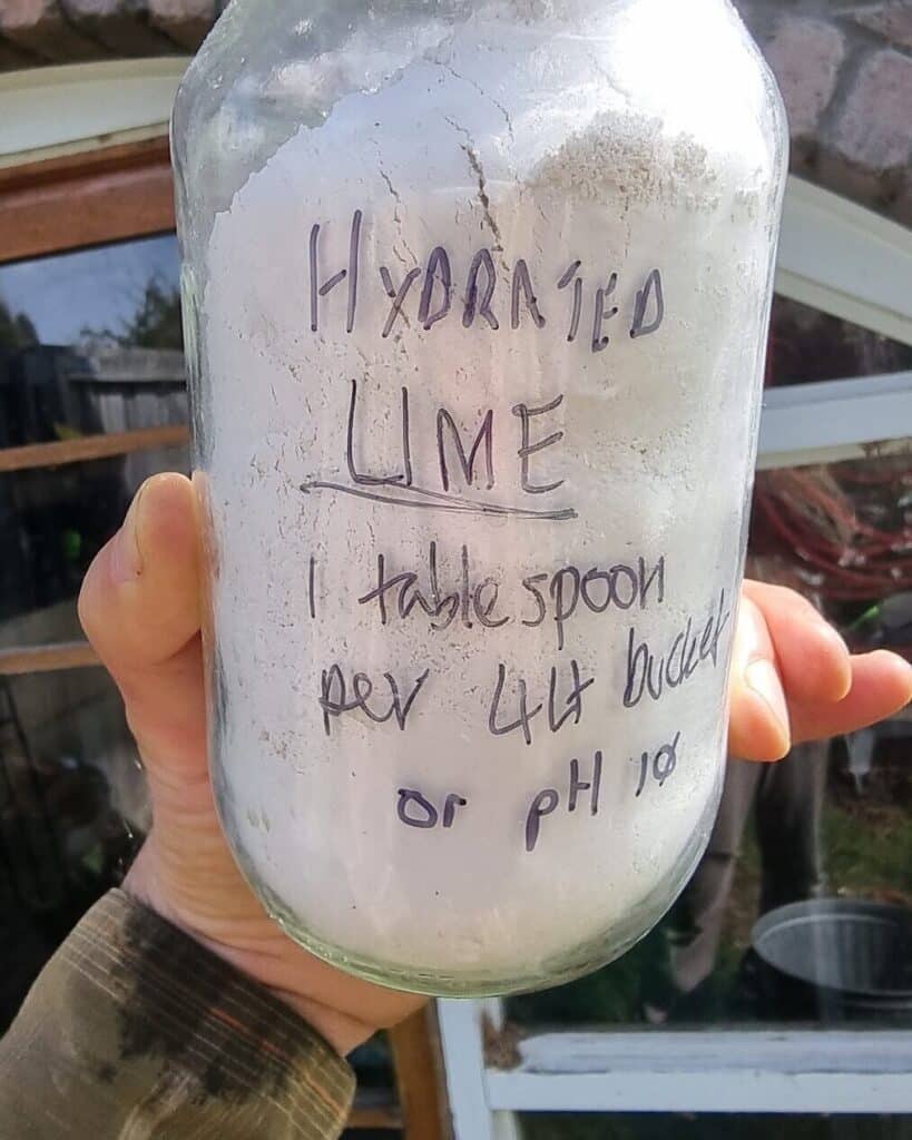 A jar of hydrated lime with a handwritten label: 1 tablespoon per 4L bucket or pH 10